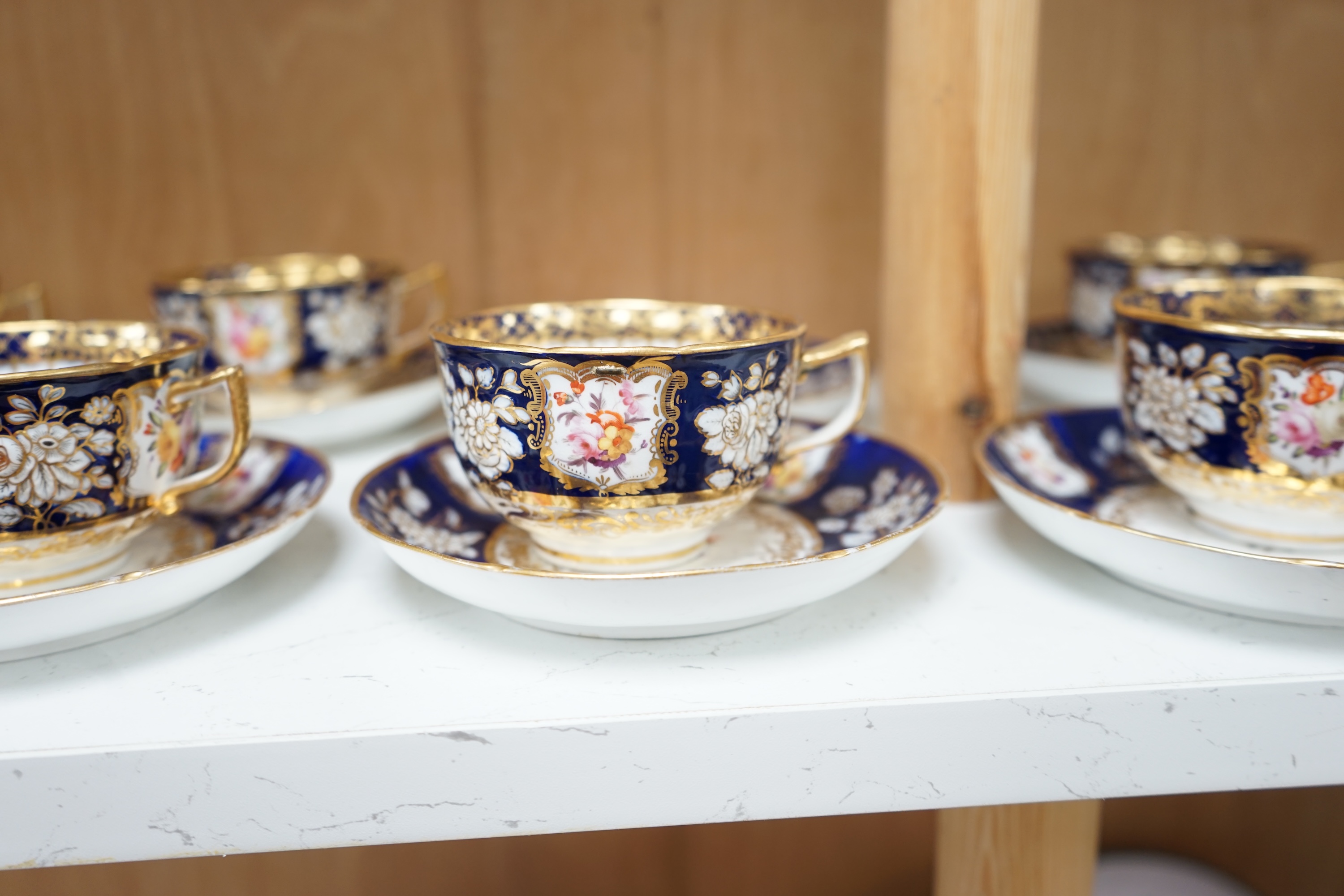 An early 19th century English porcelain tea service, possibly Coalport, moulded in low relief with floral reserves and cobalt blue border. Condition - varies